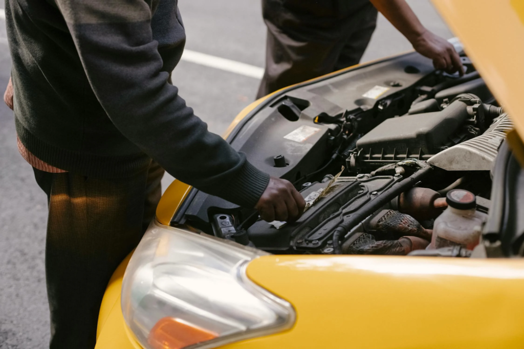 A mobile auto repair mechanic fixing an engine of a car